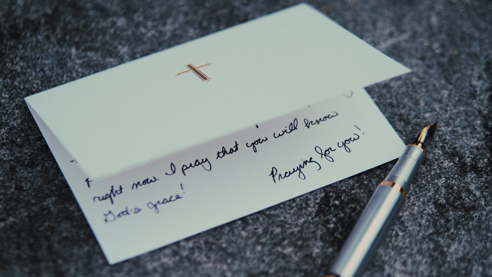 a note with a cross on it next to a pen